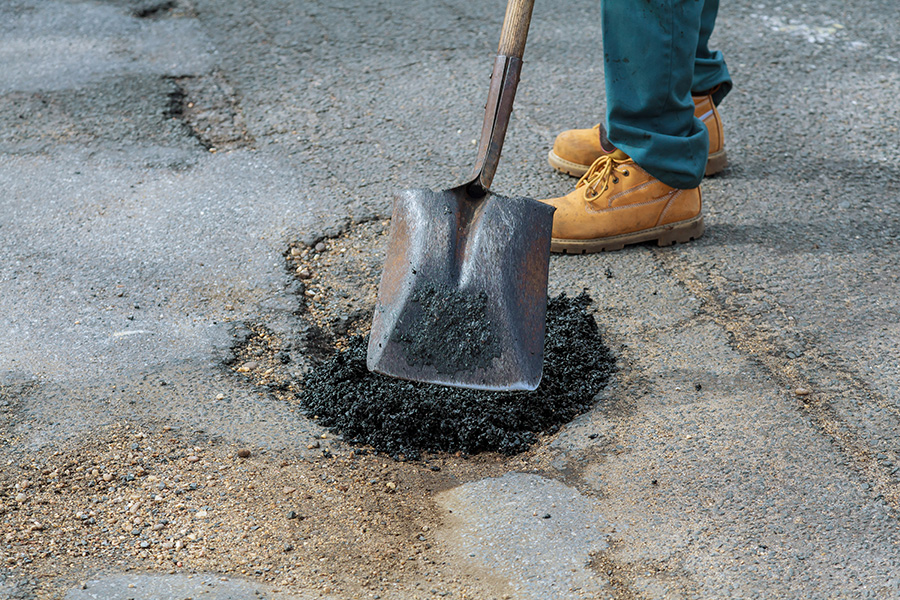 asphalt contractor patches a pothole before parking lot sealcoating